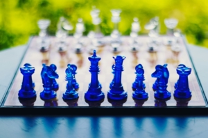 Ein Schachspiel mit blauen und weißen Figuen draußen im Park an einem sonnigen Tag